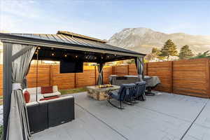 Fenced backyard featuring a gazebo, an outdoor living space with a fire pit, a patio area, and a mountain view