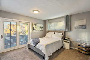 Bedroom with access to exterior, carpet flooring, a textured ceiling, and a textured wall