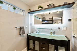 Bathroom featuring a textured wall, double vanity, and a textured ceiling