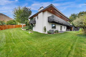 Back of property featuring a patio area, a balcony, stucco siding, a chimney, and a mountain view