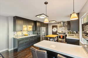Kitchen featuring decorative light fixtures, light stone countertops, stainless steel appliances, and backsplash