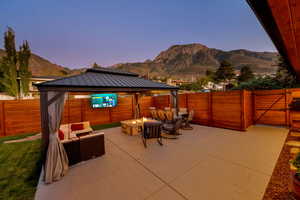 Fenced backyard with a gate, an outdoor living space with a fire pit, a patio area, and a mountain view
