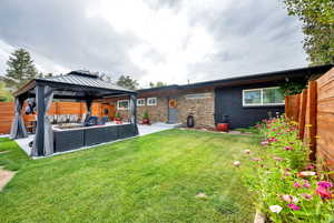 Rear view of property featuring an outdoor hangout area, a gazebo, a patio, a fenced backyard, and brick siding