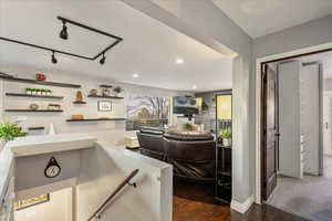 Bar area with dark wood-style flooring, open shelves, recessed lighting, rail lighting, and light countertops