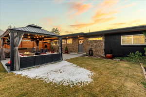 Back of property at dusk featuring an outdoor living space with a fire pit, a patio area, a gazebo, and a lawn