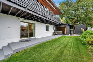 View of green lawn with a patio area and a hot tub
