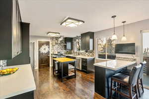 Kitchen with a kitchen breakfast bar, tasteful backsplash, dark wood-style flooring, wall chimney exhaust hood, and a peninsula