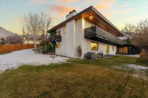 Back of property at dusk with a balcony, a chimney, a patio, and brick siding