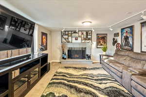 Living area featuring a fireplace, rail lighting, light colored carpet, and a textured ceiling