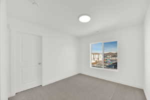 Carpeted spare room featuring baseboards