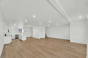 Unfurnished living room with light wood-type flooring, stairs, and recessed lighting