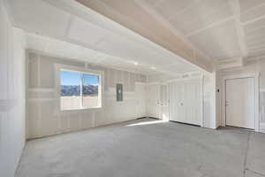 Unfurnished bedroom featuring two closets, unfinished concrete floors, and electric panel