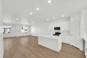 Kitchen with recessed lighting, white cabinets, a center island, stainless steel appliances, and tasteful backsplash