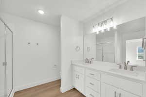 Bathroom with double vanity, a stall shower, light wood-style flooring, and recessed lighting