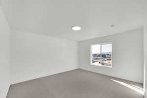 Carpeted spare room featuring baseboards