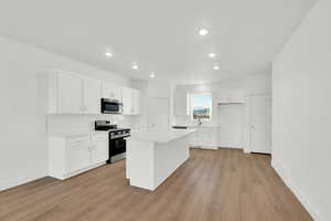 Kitchen with white cabinets, appliances with stainless steel finishes, tasteful backsplash, a center island, and recessed lighting