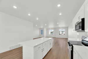 Kitchen with appliances with stainless steel finishes, white cabinetry, a center island, recessed lighting, and open floor plan