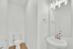 Half bath with a sink and wood finished floors