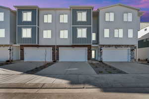 View of front of home featuring board and batten siding, driveway, an attached garage, and a residential view