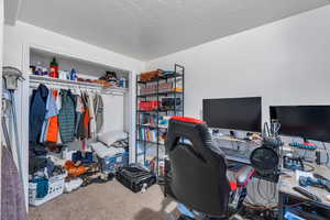 Carpeted home office with a textured ceiling