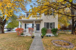 Traditional-style home featuring a porch, a fire pit, brick siding, and a front lawn