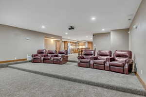 Carpeted home theater room with recessed lighting and baseboards