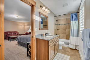 Full bathroom with vanity, shower / bath combo, ensuite bathroom, and light colored carpet