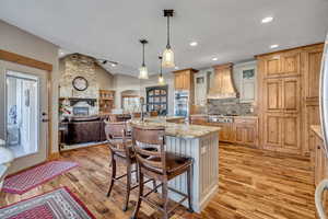 Kitchen featuring a kitchen breakfast bar, glass insert cabinets, decorative light fixtures, a kitchen island with sink, and open floor plan