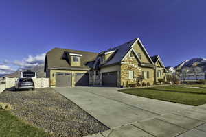 Craftsman-style home featuring concrete driveway, a mountain view, stucco siding, an attached garage, and a gate