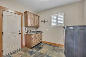 Washroom featuring washer / clothes dryer, stone tile floors, and cabinet space