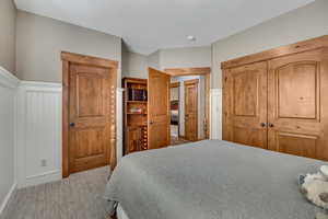 Carpeted bedroom featuring a closet and a decorative wall