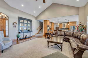Living room featuring high vaulted ceiling, recessed lighting, stairway, arched walkways, and light wood-type flooring