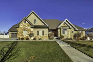 Craftsman house featuring a front yard, stucco siding, stone siding, and covered porch