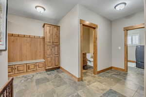 Mudroom featuring a textured ceiling, washer / clothes dryer, and stone tile flooring