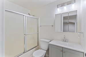 Full bath with vanity and combined bath / shower with glass door