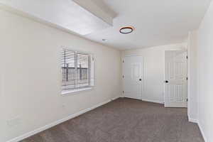 Unfurnished bedroom featuring dark colored carpet and baseboards