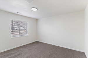 Spare room featuring carpet floors and baseboards