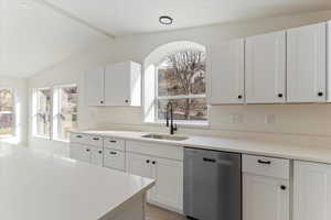 Kitchen with dishwasher, white cabinets, light stone countertops, and light wood-style flooring