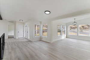 Unfurnished living room with light wood-type flooring and vaulted ceiling