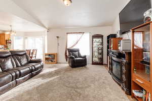 Living room with plenty of natural light, light colored carpet, and a chandelier