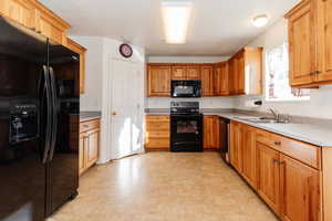 Kitchen featuring black appliances, light countertops, brown cabinets, and light flooring