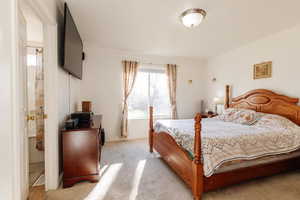 Bedroom featuring light carpet and ensuite bathroom
