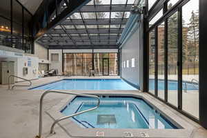 Indoor pool with a patio and an in-ground hot tub