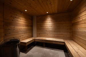 Sauna / steam room featuring wooden walls, wood ceiling, recessed lighting, and unfinished concrete floors