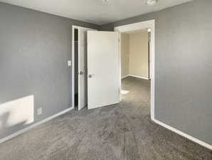 Unfurnished bedroom with a textured wall, a textured ceiling, and carpet