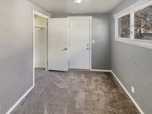 Unfurnished bedroom featuring a textured wall, carpet flooring, a textured ceiling, and a closet