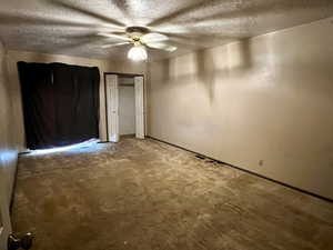 Unfurnished bedroom with a textured ceiling, carpet floors, and ceiling fan