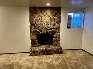 Unfurnished living room with wooden walls, carpet flooring, a fireplace, and a textured ceiling