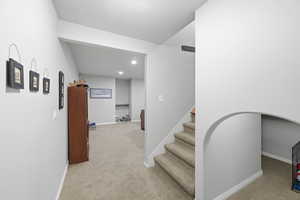 Corridor featuring light colored carpet, recessed lighting, and stairs