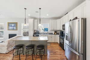 Kitchen with black appliances, a breakfast bar area, decorative light fixtures, open floor plan, and a kitchen island